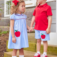 Little English traditional children's clothing. Light blue chambray dress for toddler girl . Back to school dress with red apple applique and red piping for fall.