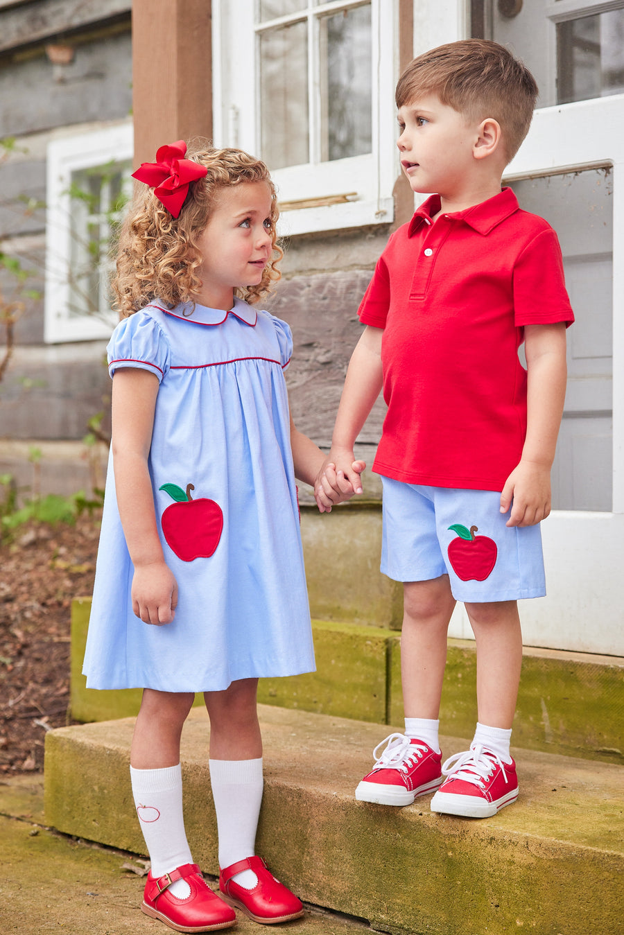 Little English traditional children's clothing. Light blue chambray dress for toddler girl . Back to school dress with red apple applique and red piping for fall.