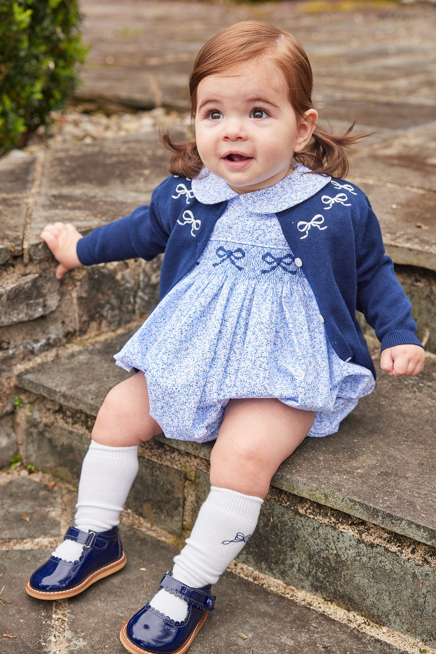 Little English traditional children's clothing. Classic smockked blue floral peter pan bubble with navy bows for little girl for Fall