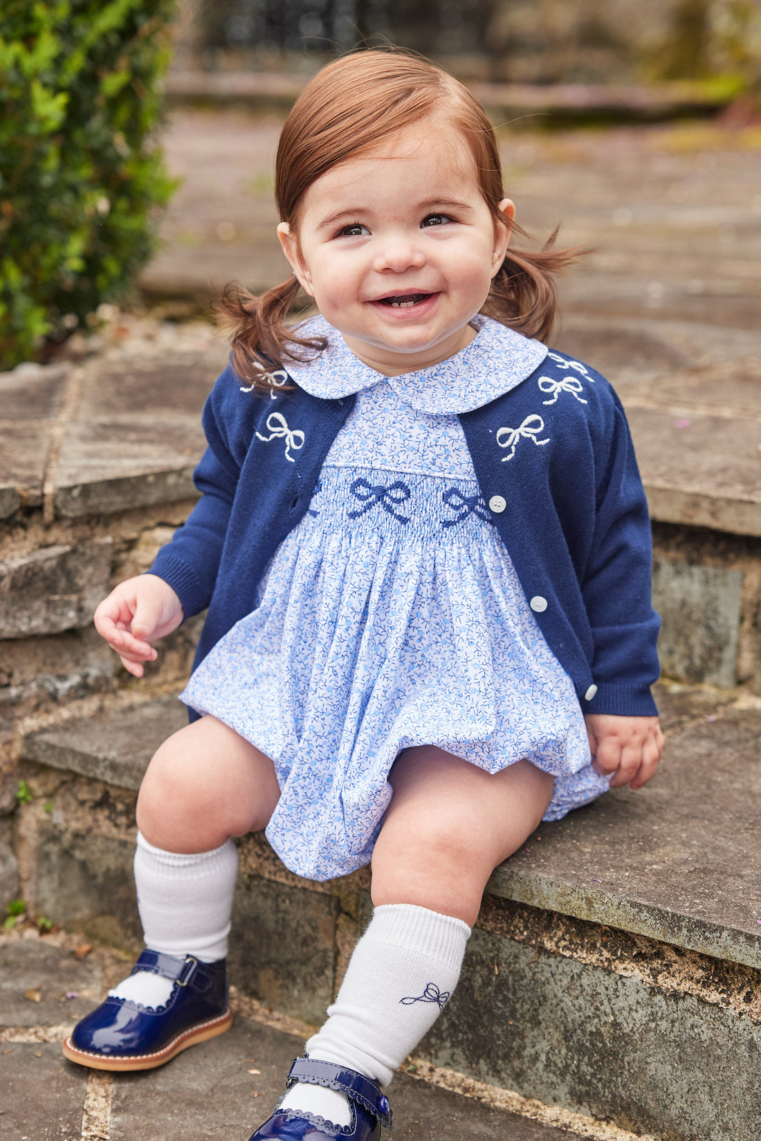 Little English traditional clothing, knit essential cardigan in navy with white bow embroidery around neckline and white buttons down the center, for little girl