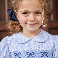 Little English traditional children's clothing. Classic smockked blue floral peter pan dress with navy bows for little girl for Fall