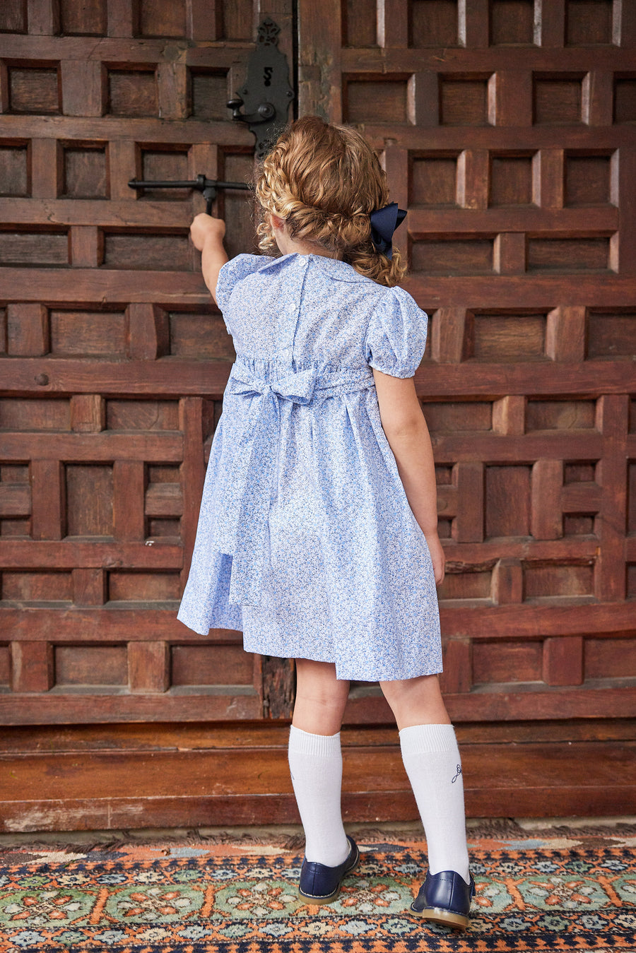 Little English traditional children's clothing. Classic smockked blue floral peter pan dress with navy bows for little girl for Fall