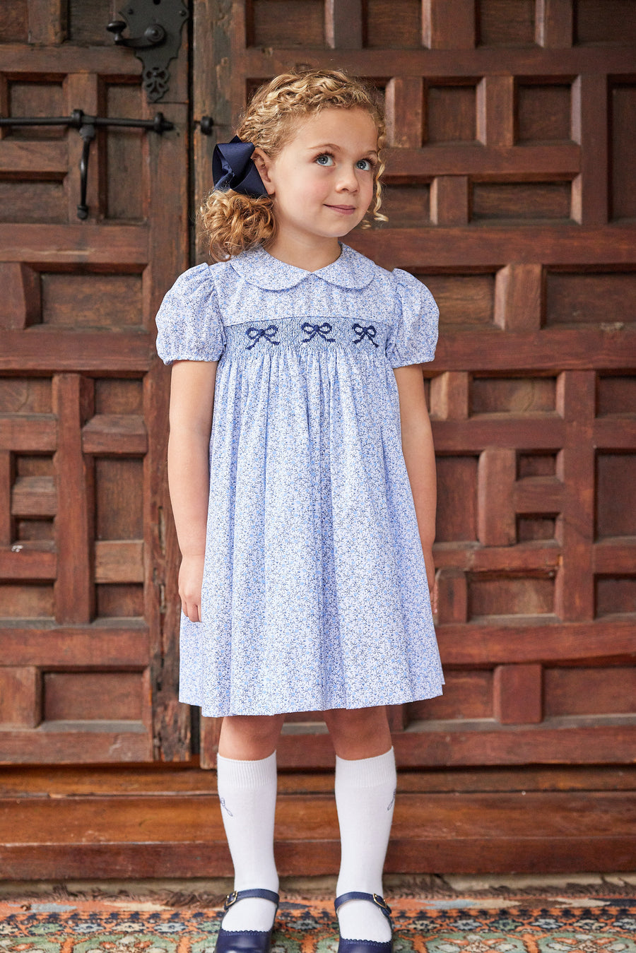 Little English traditional children's clothing. Classic smockked blue floral peter pan dress with navy bows for little girl for Fall